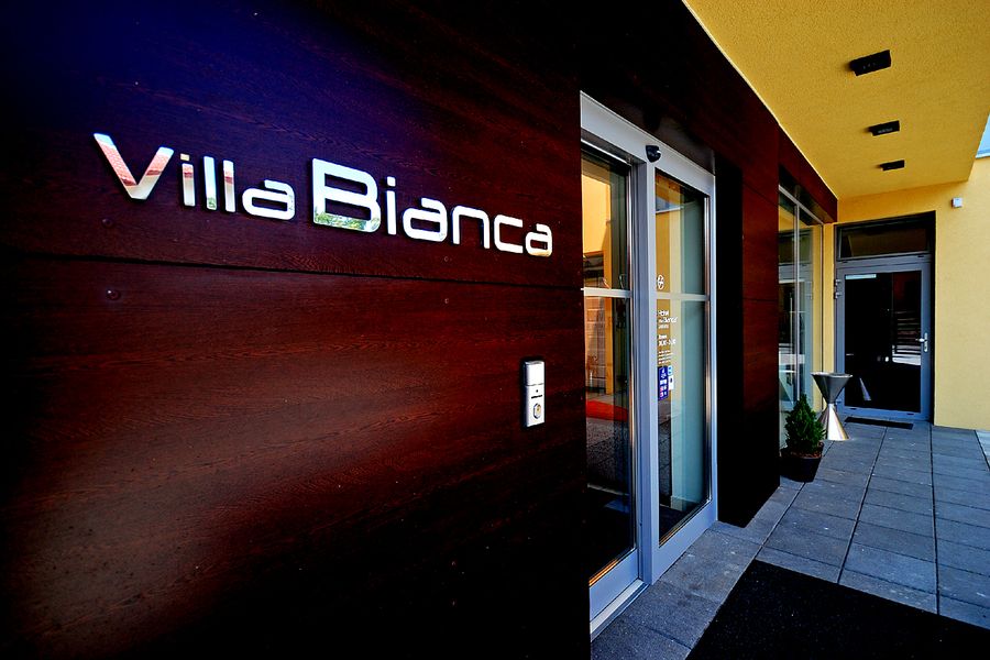 Vstup do hotela s nápisom Villa Bianca na tmavom dreve